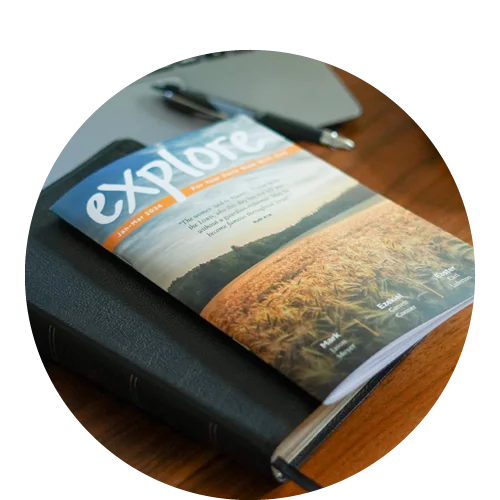 an issue of Explore Bible Notes is setting on a soft-cover bible on a wooden table